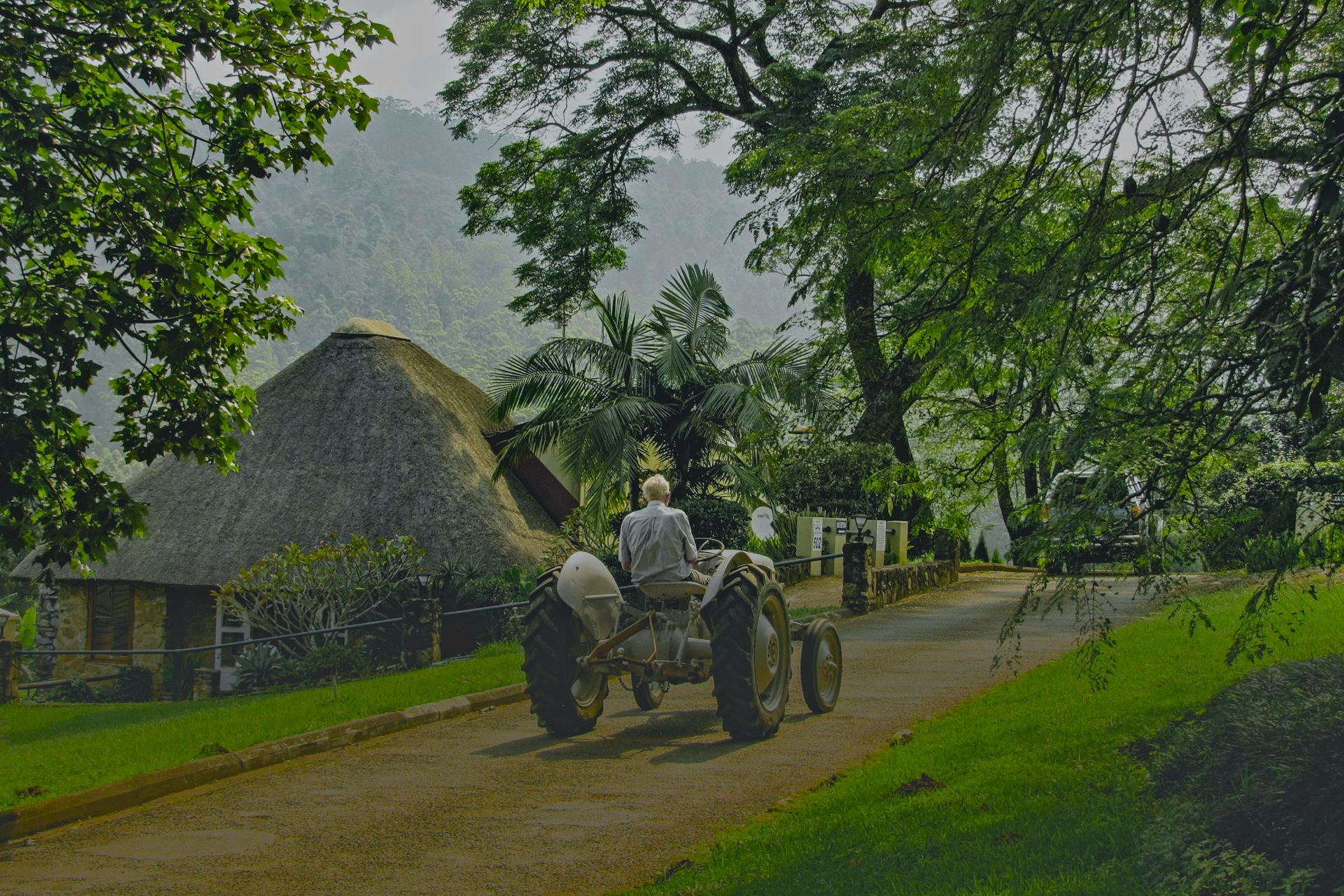 Farmer on tractor driving through misty farmstead